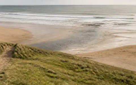 Darker, calmer channel of water cutting through breaking waves towards the open sea on a sandy beach