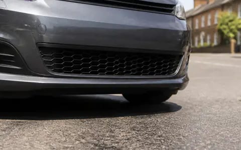 The dark grille and lower bumper of a grey car, where the outside temperature sensor often sits